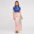 May include: A blue short-sleeved cropped top with a front zipper and a white flower graphic, paired with a light pink wrap skirt featuring a green leaf pattern, a small orange flower detail, and a fringed hemline at the bottom of the skirt.