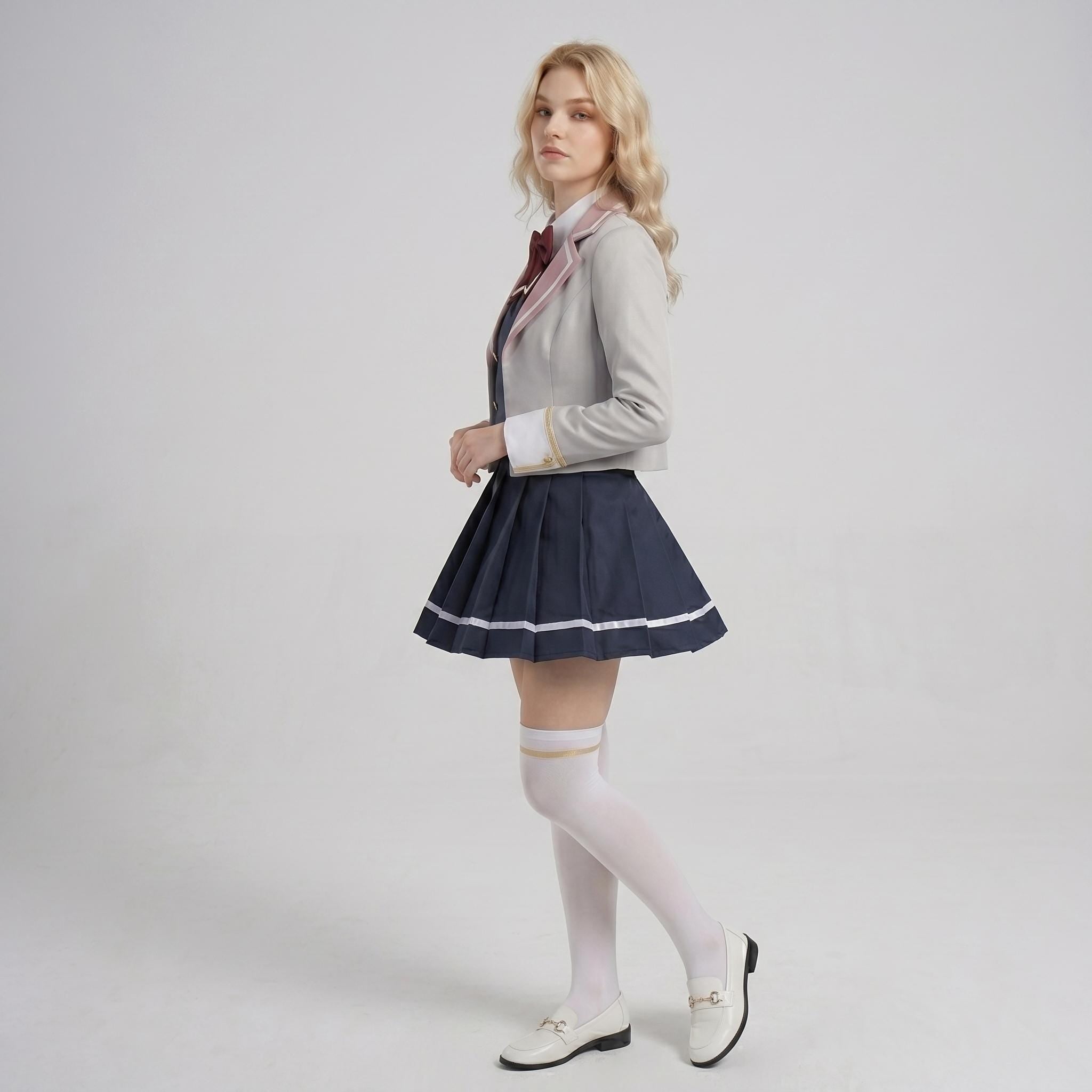 May include: A light gray blazer with a maroon tie and white shirt collar, paired with a navy blue pleated skirt featuring a white horizontal stripe near the hem. The outfit includes white knee-high socks with a gold band and white loafers.