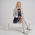 May include: A light gray blazer with pink lapel trim, a dark blue sleeveless dress with a white collar, and a maroon bow tie. The outfit includes a pleated dark blue skirt with a white hem stripe, white over-the-knee socks, and white loafers.