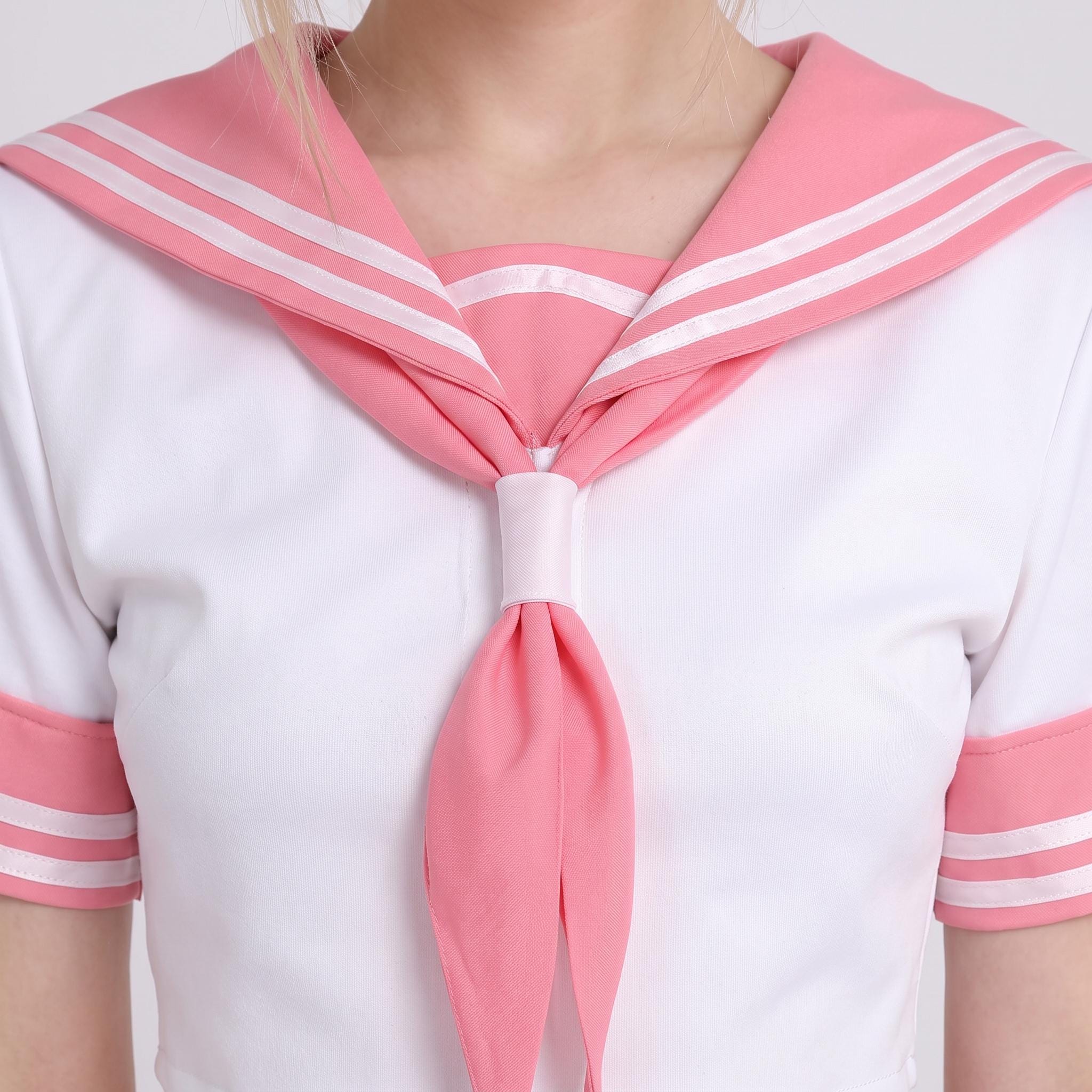 May include: A white short-sleeved top featuring a large pink sailor-style collar with two horizontal white stripes. The garment includes a matching pink neckerchief secured by a central pink fabric loop, and pink sleeve cuffs with white stripes.