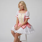 May include: A short-sleeved dress featuring a pale yellow bodice with a vertical row of pink buttons, framed by white ruffled trim. The skirt is pink with petal-shaped overlays and a white ruffled hem, complemented by a red choker collar.
