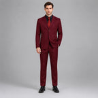 May include: A deep burgundy two-piece suit consisting of a single-breasted blazer with two buttons and matching trousers. The blazer features notched lapels and is worn over a black button-down shirt with a solid red necktie and black dress shoes.