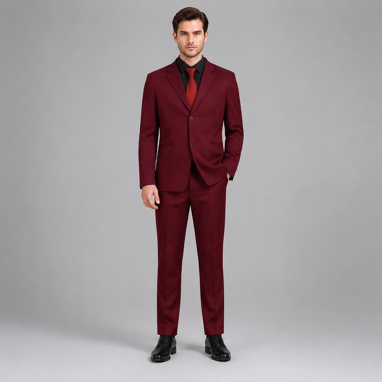 May include: A deep burgundy two-piece suit consisting of a single-breasted blazer with two buttons and matching trousers. The blazer features notched lapels and is worn over a black button-down shirt with a solid red necktie and black dress shoes.
