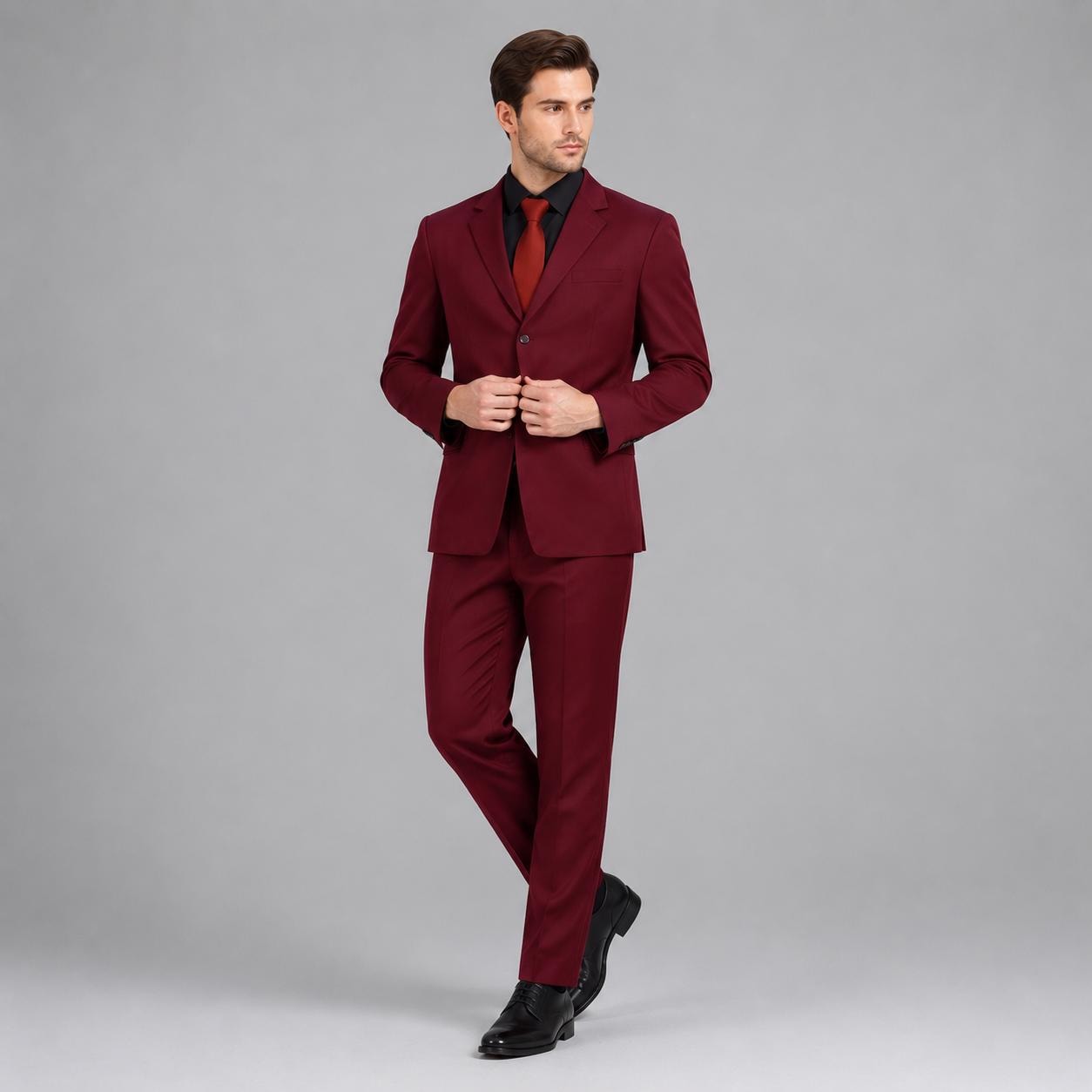 May include: A deep burgundy suit consisting of a single-breasted blazer with notched lapels and matching trousers. The blazer features a single button closure and is paired with a solid red necktie and a crisp white collared dress shirt.