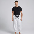 May include: A black short-sleeved crew neck t-shirt paired with loose-fitting white trousers. The trousers feature a high-waisted design with a black fabric belt tied in a bow at the center front and gathered elastic cuffs at the ankles.