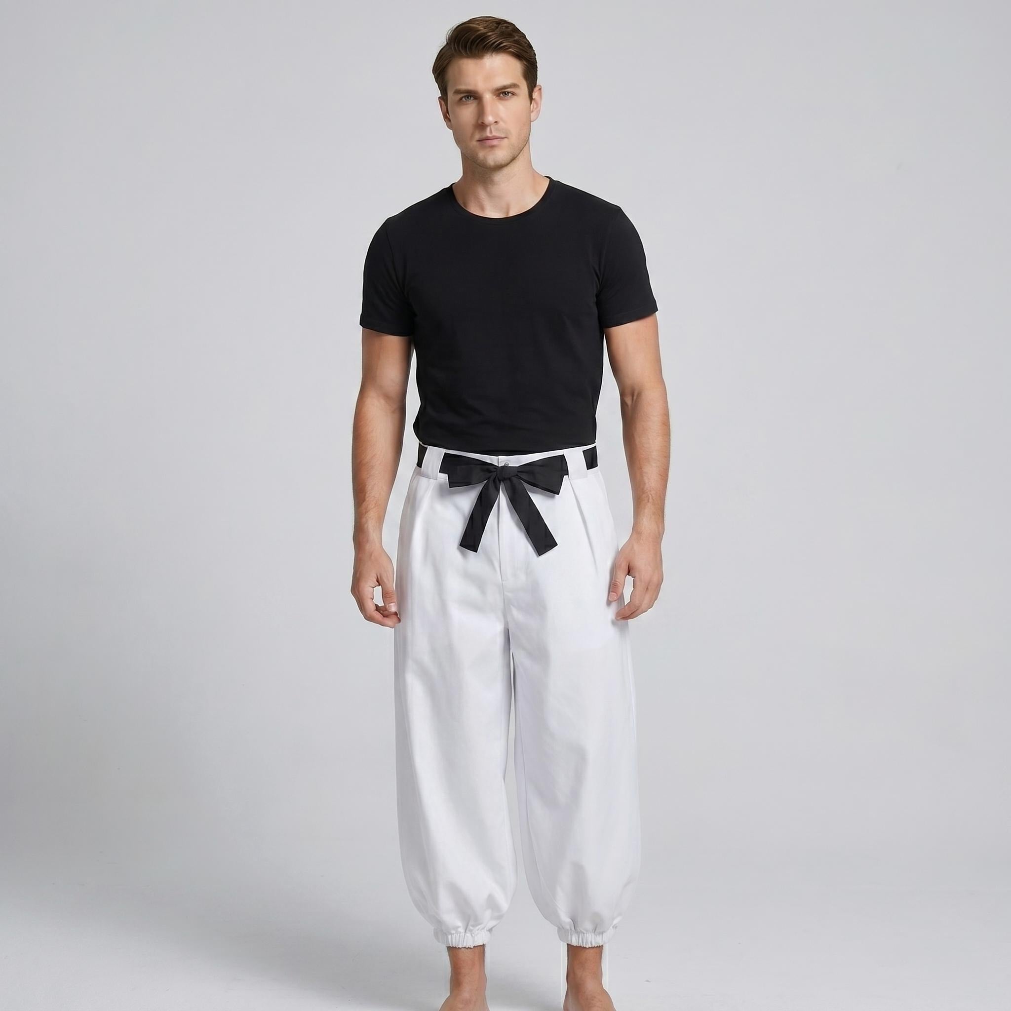 May include: A black short-sleeved crew neck t-shirt paired with loose-fitting white trousers. The trousers feature a high-waisted design with a black fabric belt tied in a bow at the center front and gathered elastic cuffs at the ankles.