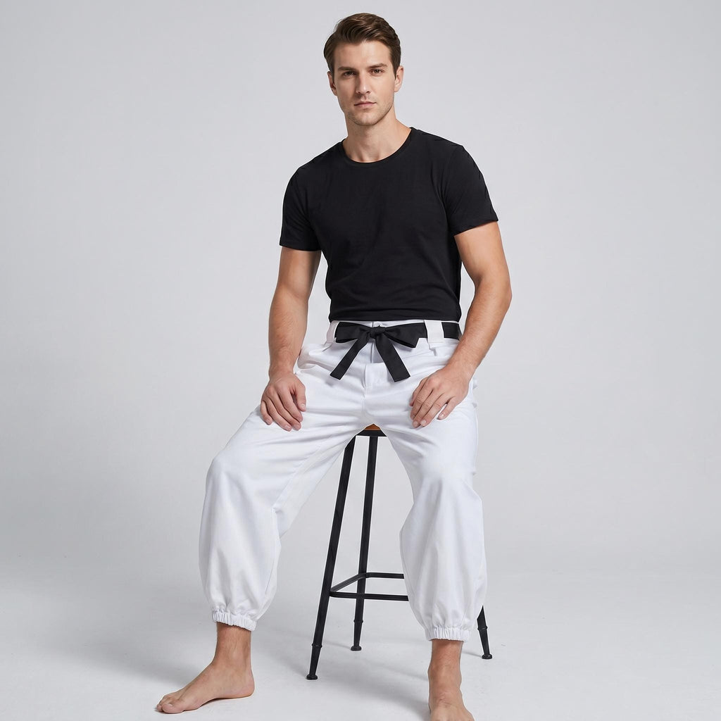 May include: A black short-sleeved t-shirt paired with white trousers featuring an elasticized waistband and cuffs. The trousers include a black fabric belt tied in a bow at the front, creating a distinct contrast against the white fabric.