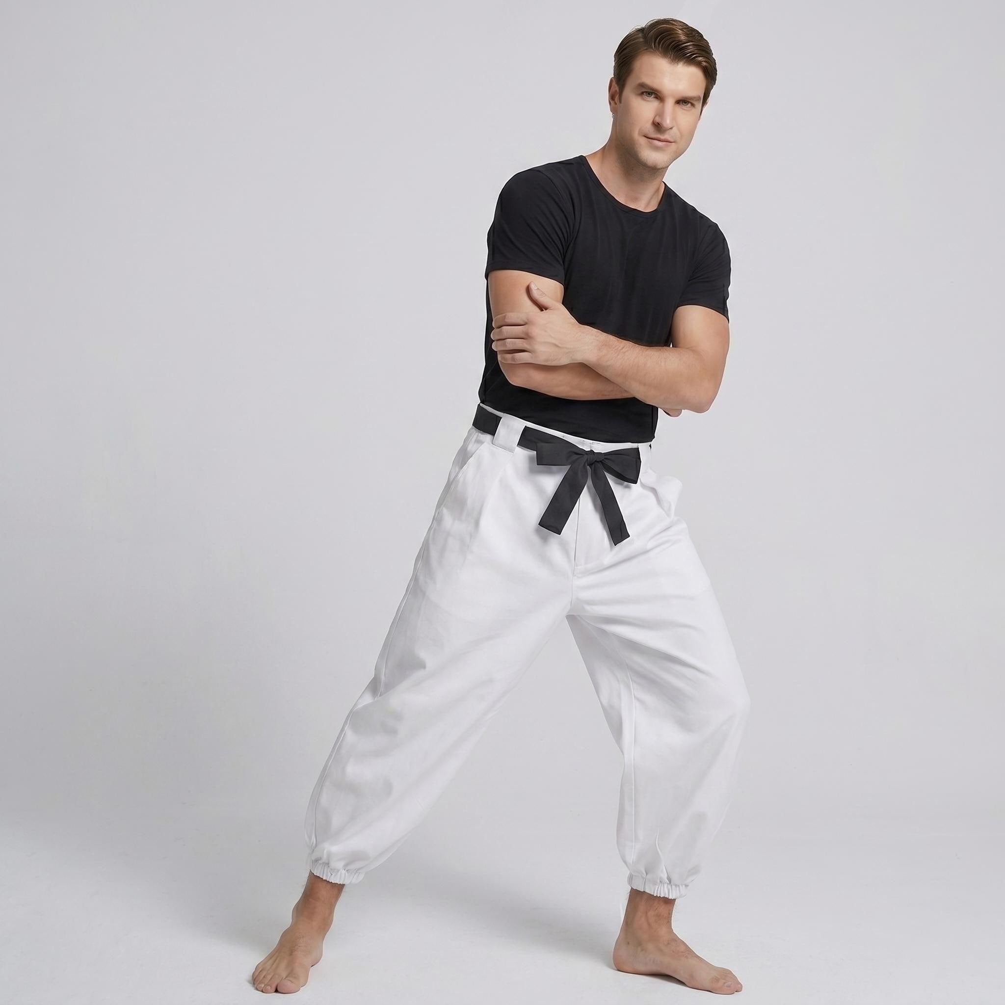 May include: A black short-sleeved crew neck t-shirt paired with loose-fitting white trousers featuring a black fabric belt tied at the waist. The trousers have a gathered elastic cuff at the ankles and a structured waistband with belt loops.
