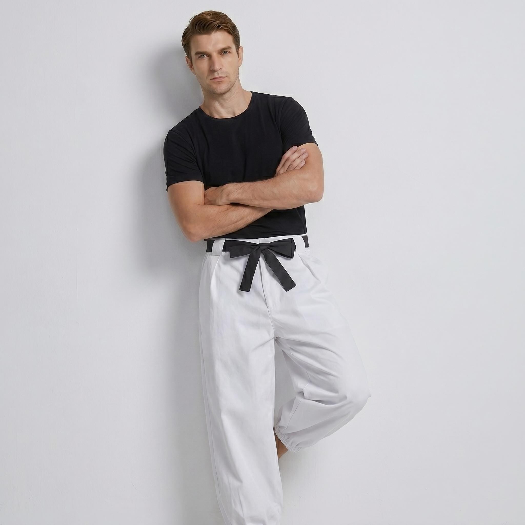 May include: A black short-sleeved t-shirt paired with white trousers featuring a high-waisted design and a black fabric tie belt at the waist. The trousers have a relaxed fit with gathered cuffs at the ankles, creating a distinct contrast between the dark top and the light-colored bottoms.