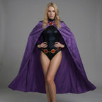 May include: A woman wearing a black bodysuit with a long-sleeved top and a purple cape. The cape is draped over the shoulders and extends to the ground. The bodysuit has a gold belt with red accents. A red jewel is at the neckline.