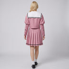 May include: A dusty rose sailor-style outfit consisting of a long-sleeved cropped jacket with a large white square collar featuring black trim, and a matching pleated skirt with a thin black horizontal stripe near the hem, worn with white socks.